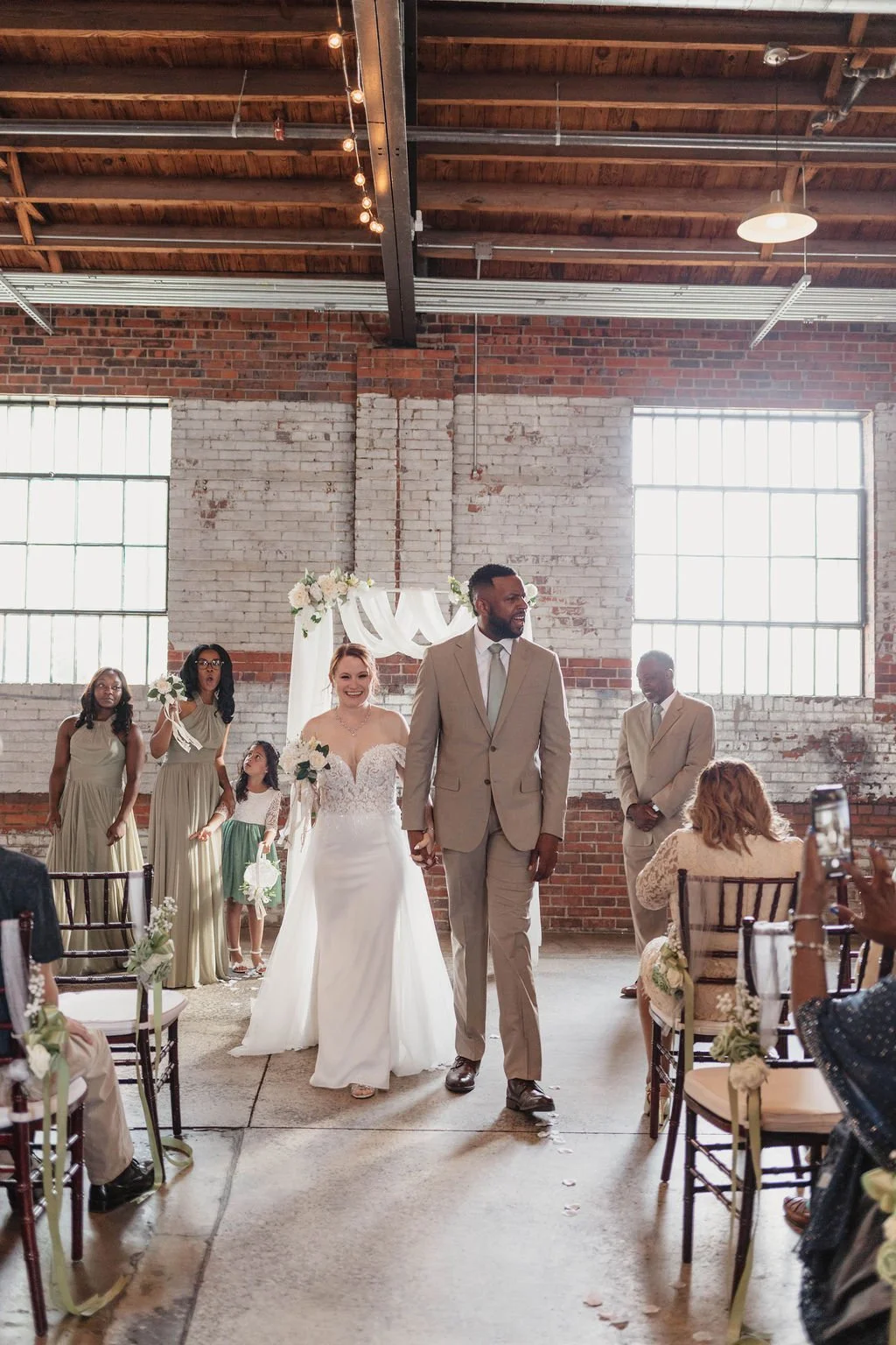 Industrial warehouse wedding venue at Studio 215 in Fayetteville, NC, located near Raleigh and Fort Bragg, featuring exposed brick, bistro lighting, and a modern chic aesthetic for weddings and events. 