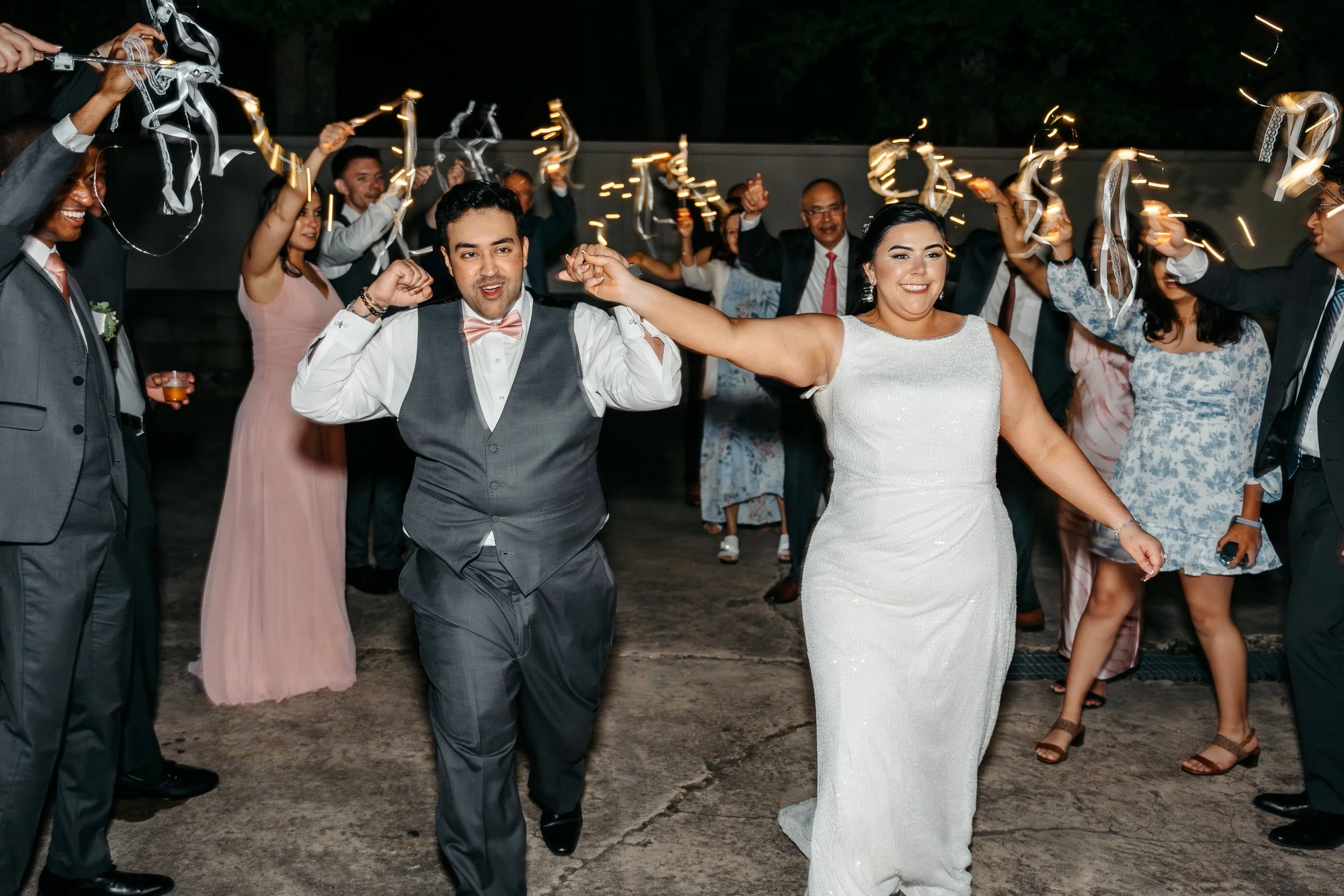 Wedding reception with bride and groom dancing surrounded by guests holding sparklers.