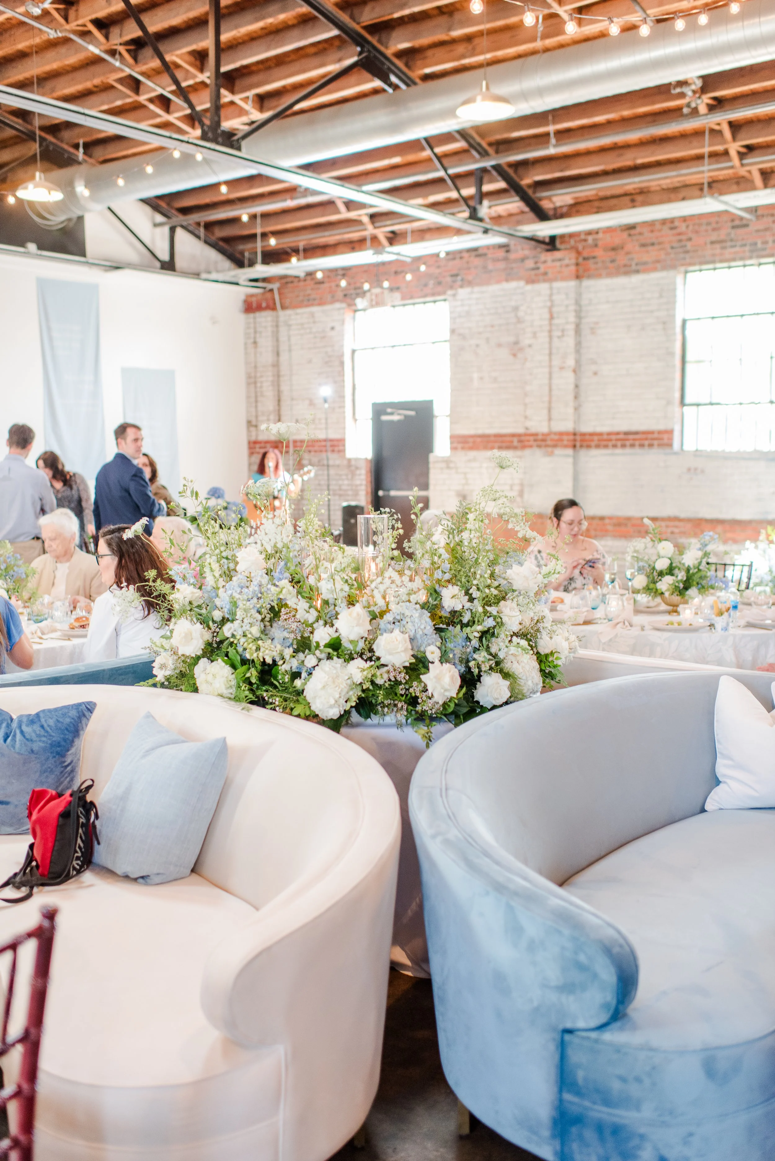 Industrial warehouse wedding venue at Studio 215 in Fayetteville, NC, located near Raleigh and Fort Bragg, featuring exposed brick, bistro lighting, and a modern chic aesthetic for weddings and events. 