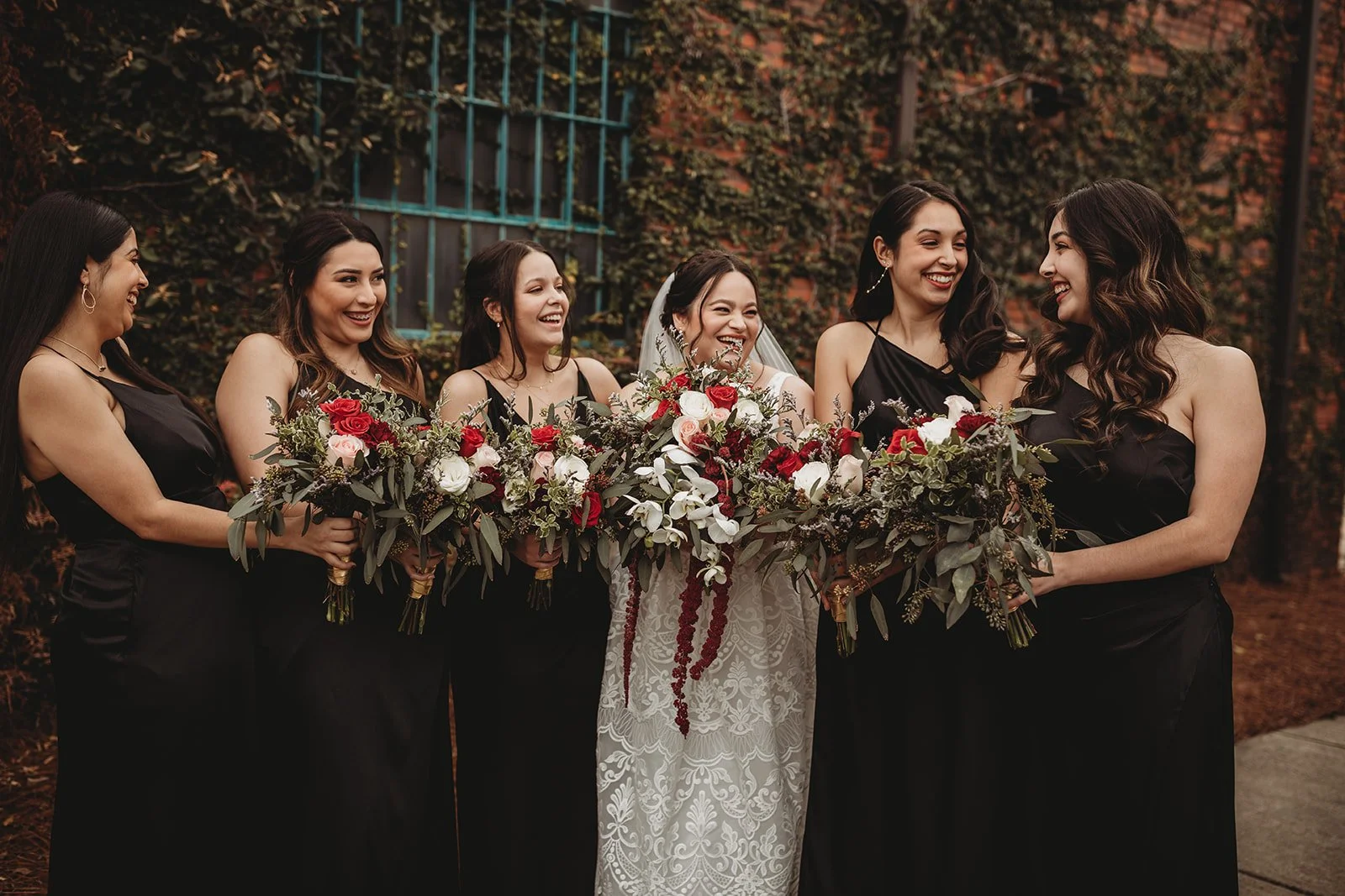 Bride and groom posing in front of the signature green ivy wall at Studio 215 in downtown Fayetteville, NC; a lush urban garden photography backdrop at our industrial warehouse venue near Fort Bragg and Raleigh.