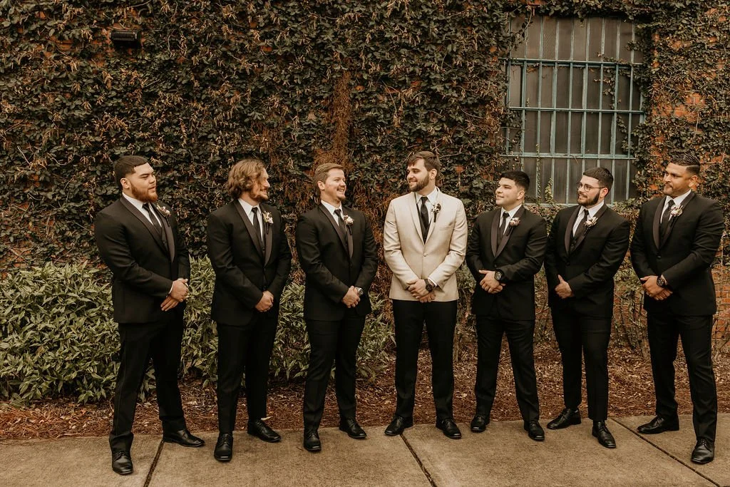 Bride and groom posing in front of the signature green ivy wall at Studio 215 in downtown Fayetteville, NC; a lush urban garden photography backdrop at our industrial warehouse venue near Fort Bragg and Raleigh.