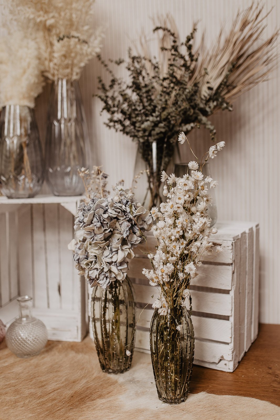 Vasen mit getrockneten Blumen auf Holzkisten