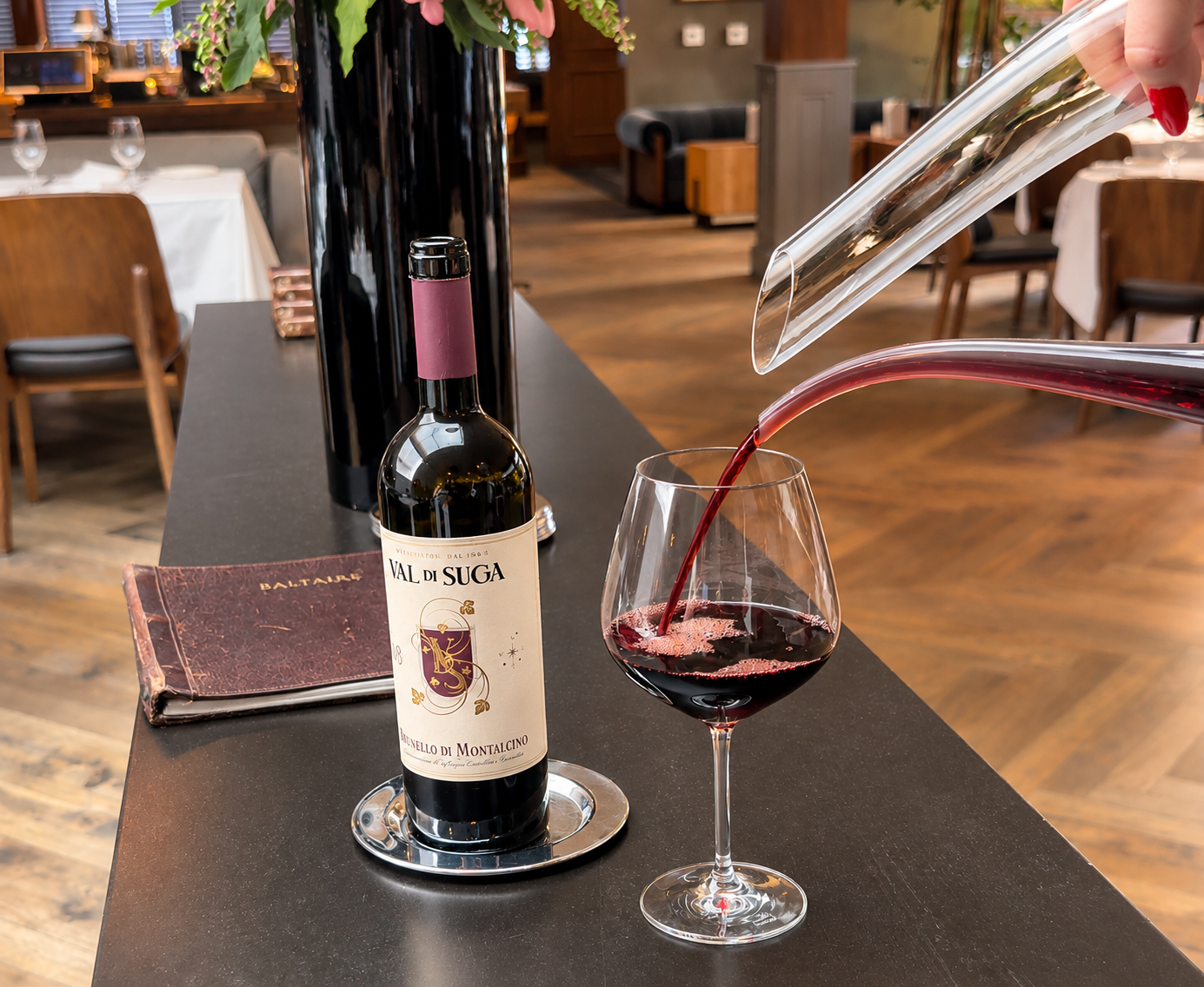 Pouring red wine from a decanter at Baltaire Restaurant, an award-winning steakhouse in Los Angeles