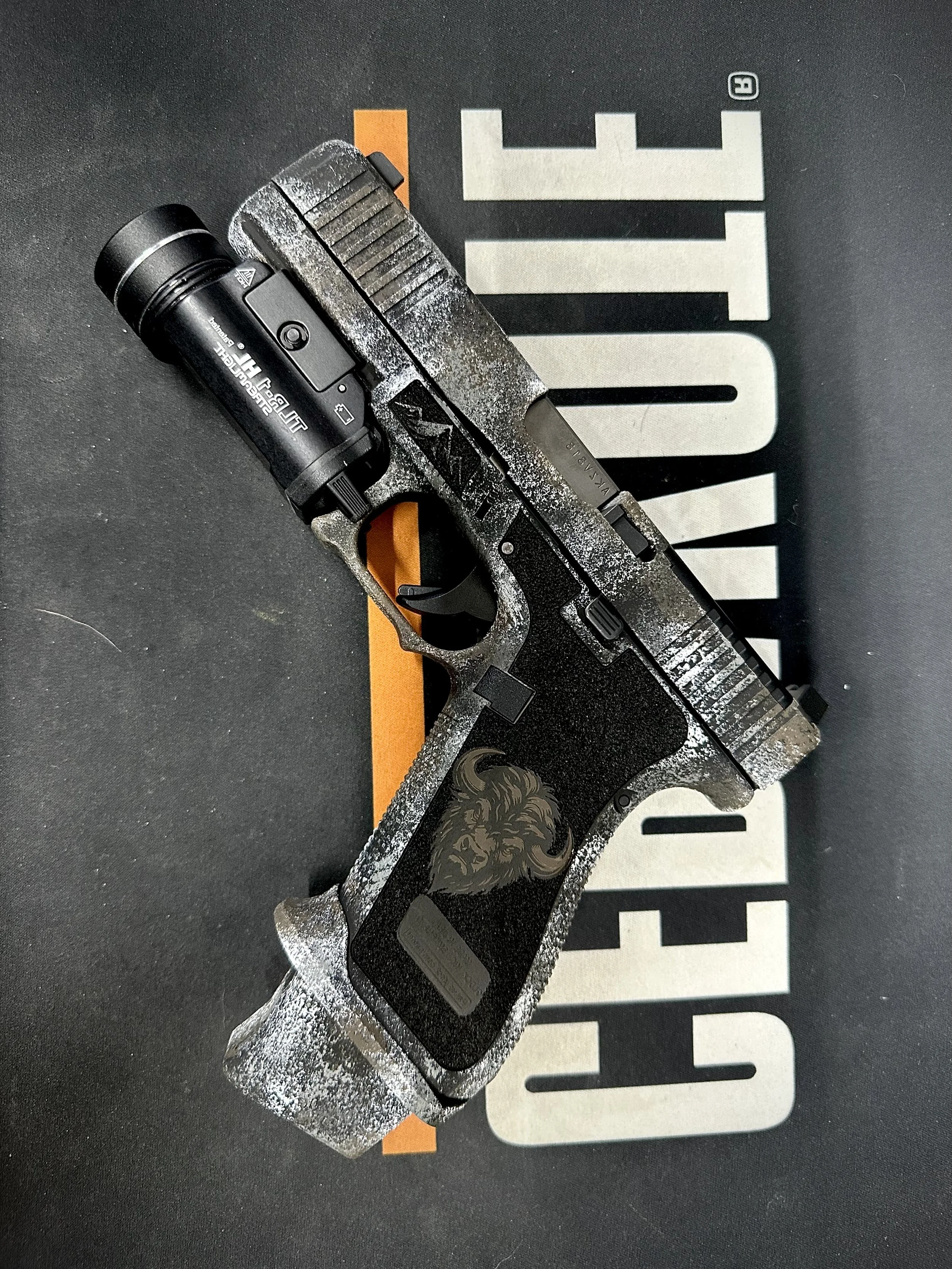 A handgun resting on a black surface with the word 'GUNFIRE' in large letters underneath.