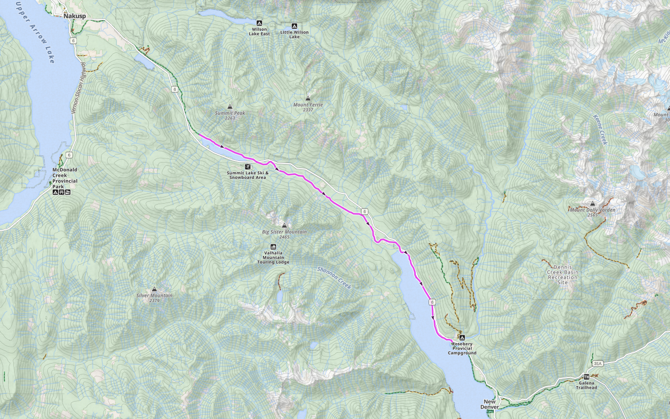 Topographic map of a mountainous area with a highlighted trail route running from New Denver in the south to Nakusp in the north, passing through campsites, ski areas, and mountain peaks.