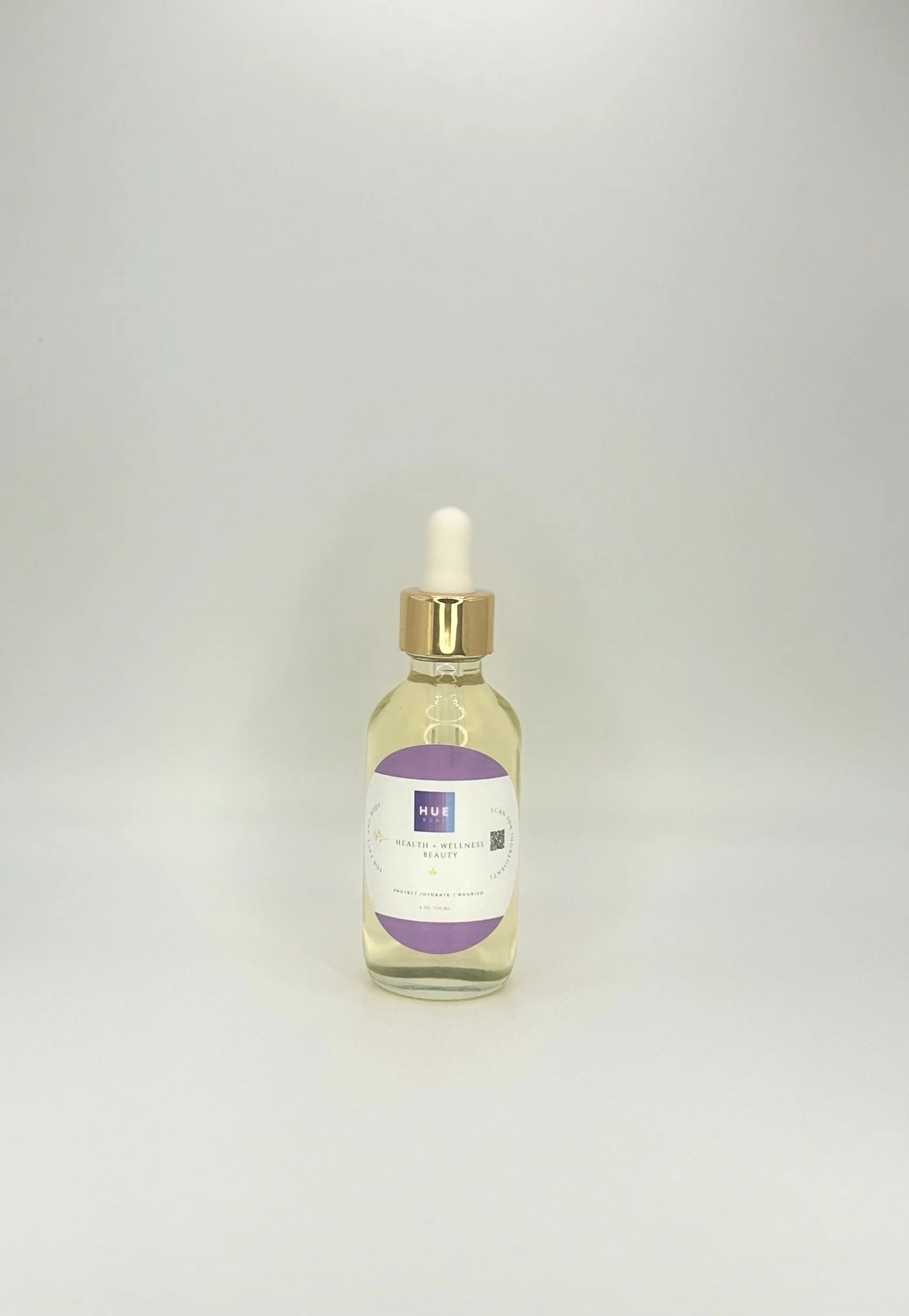 A small glass bottle with a gold cap and a white dropper, containing a clear liquid, with a purple and white label marked 'HUE' and text related to health, wellness, and beauty.