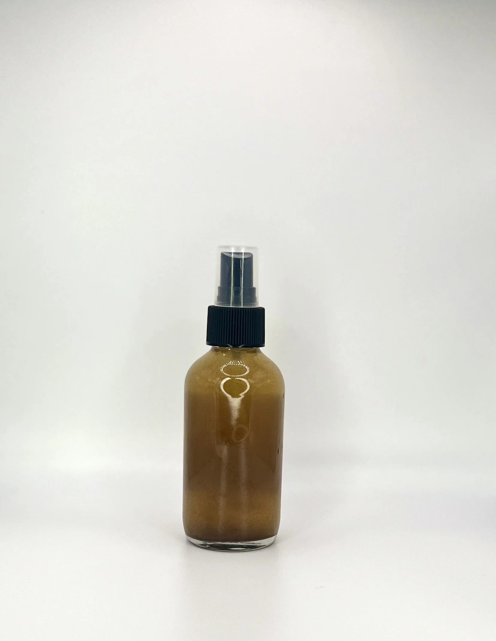 Brown spray bottle with black spray nozzle and clear cap on a white background.