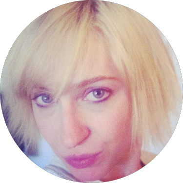 Close-up of a woman with blonde hair and blue eyes, looking at the camera.