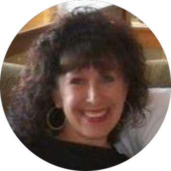 Smiling woman with curly dark hair wearing hoop earrings, indoors.