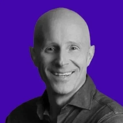 Michael Daingerfield smiling in a black-and-white headshot against a purple background.