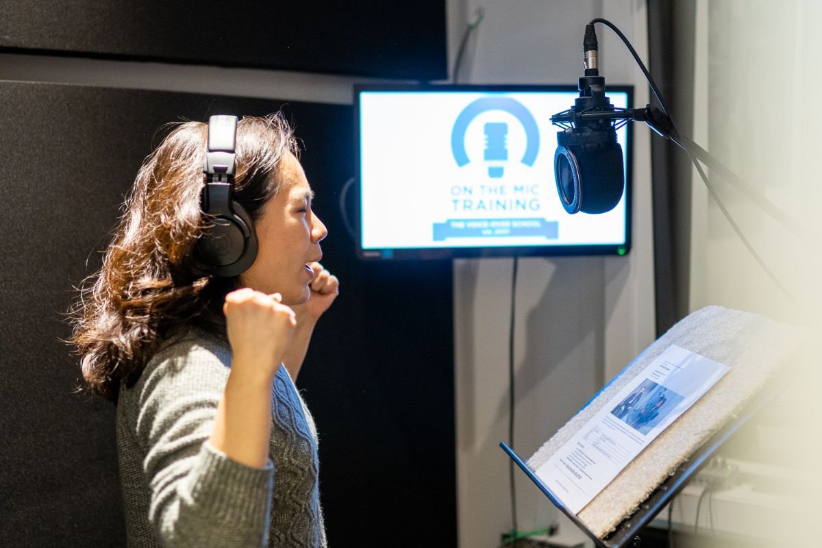 Woman wearing headphones recording dialogue while watching a screen during a Dubbing and ADR class