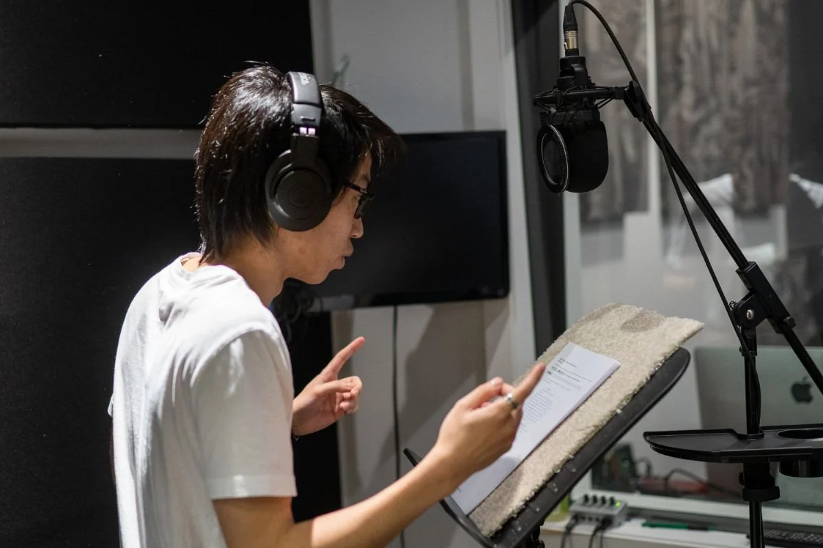Voice actor wearing headphones reading from a script during a Video Game Voice-Over class