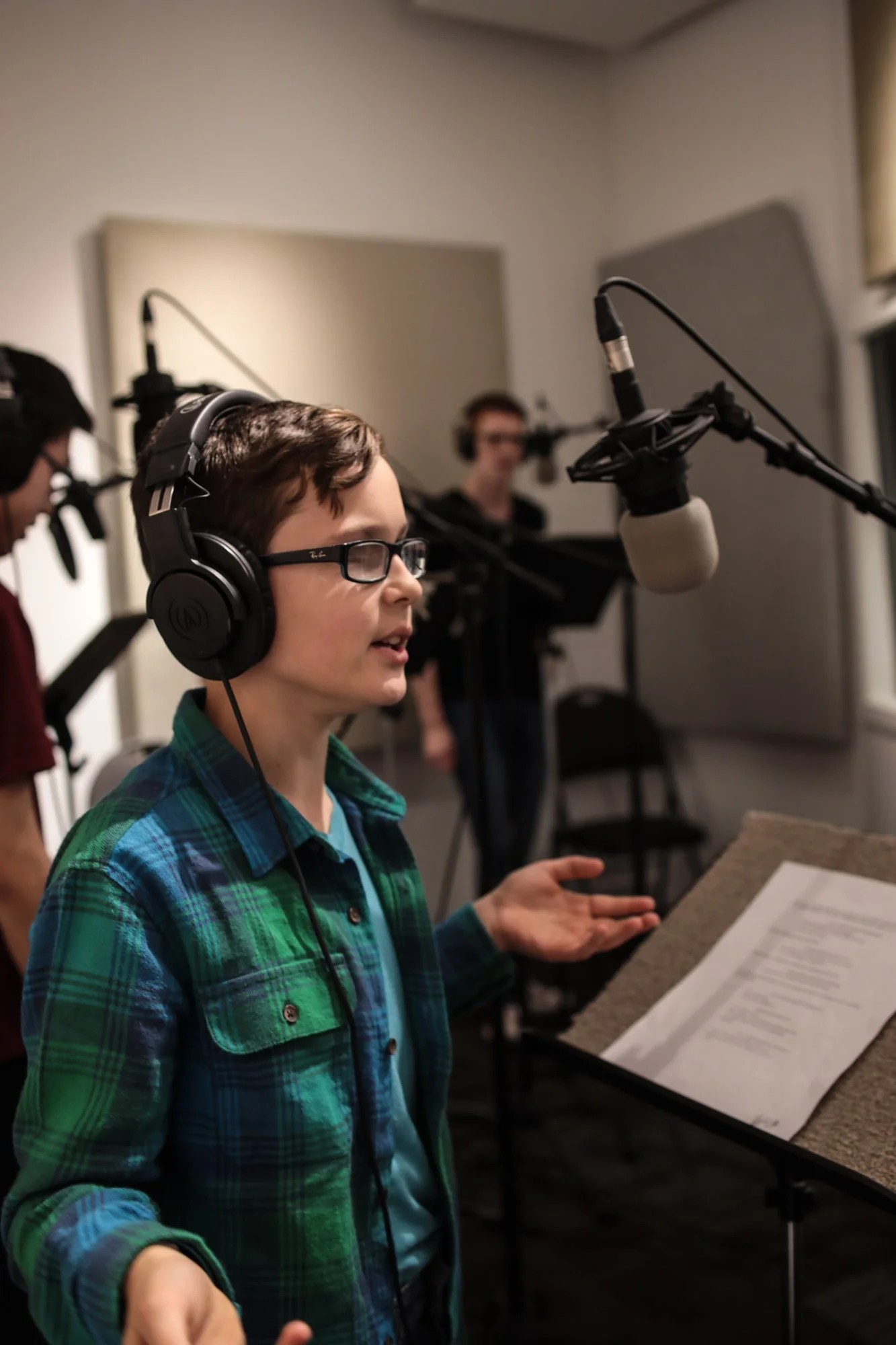 Young voice actor wearing headphones performing at a studio microphone during a Kids & Teens Voice-Over Level 1 class