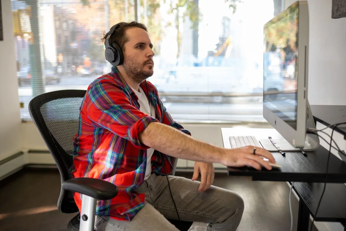 Man wearing headphones working at a computer during a sound design class