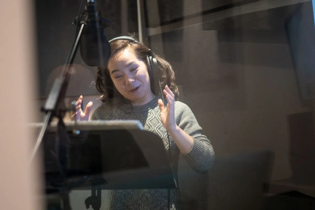Woman performing expressively at a microphone during an audiobook narration class