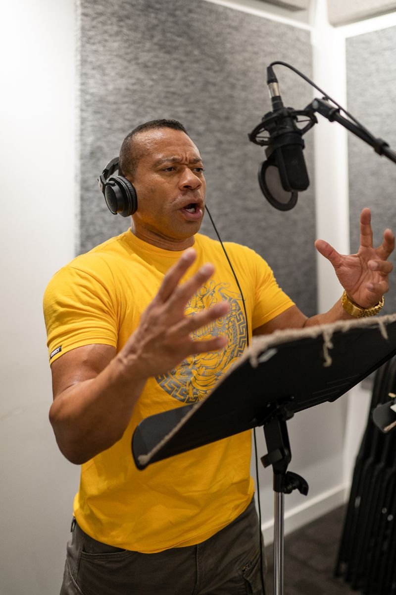 Man gesturing while performing at a studio microphone during an Animation Voice-Over Level 2 class