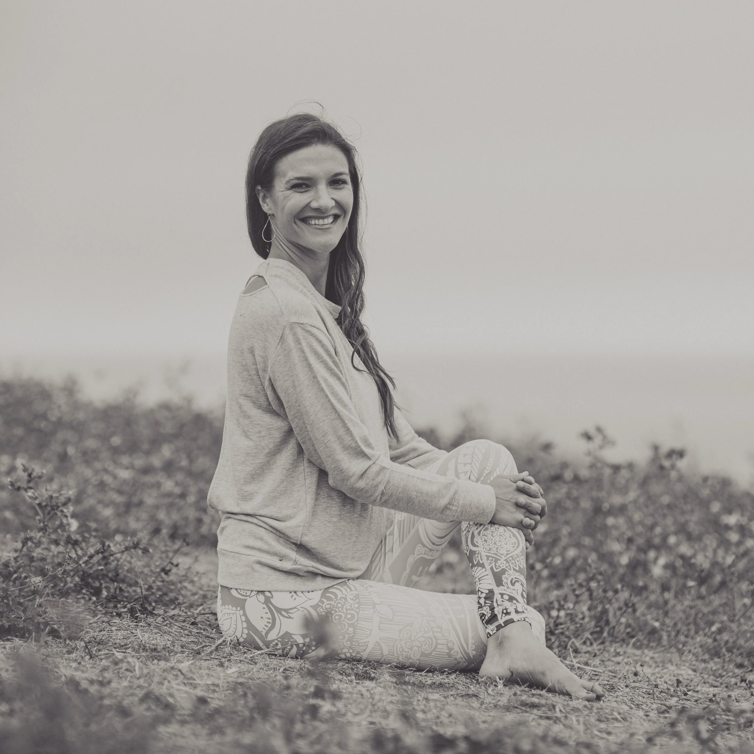 Josie Kramer, somatic facilitator, in a grounded moment of reflection by the ocean