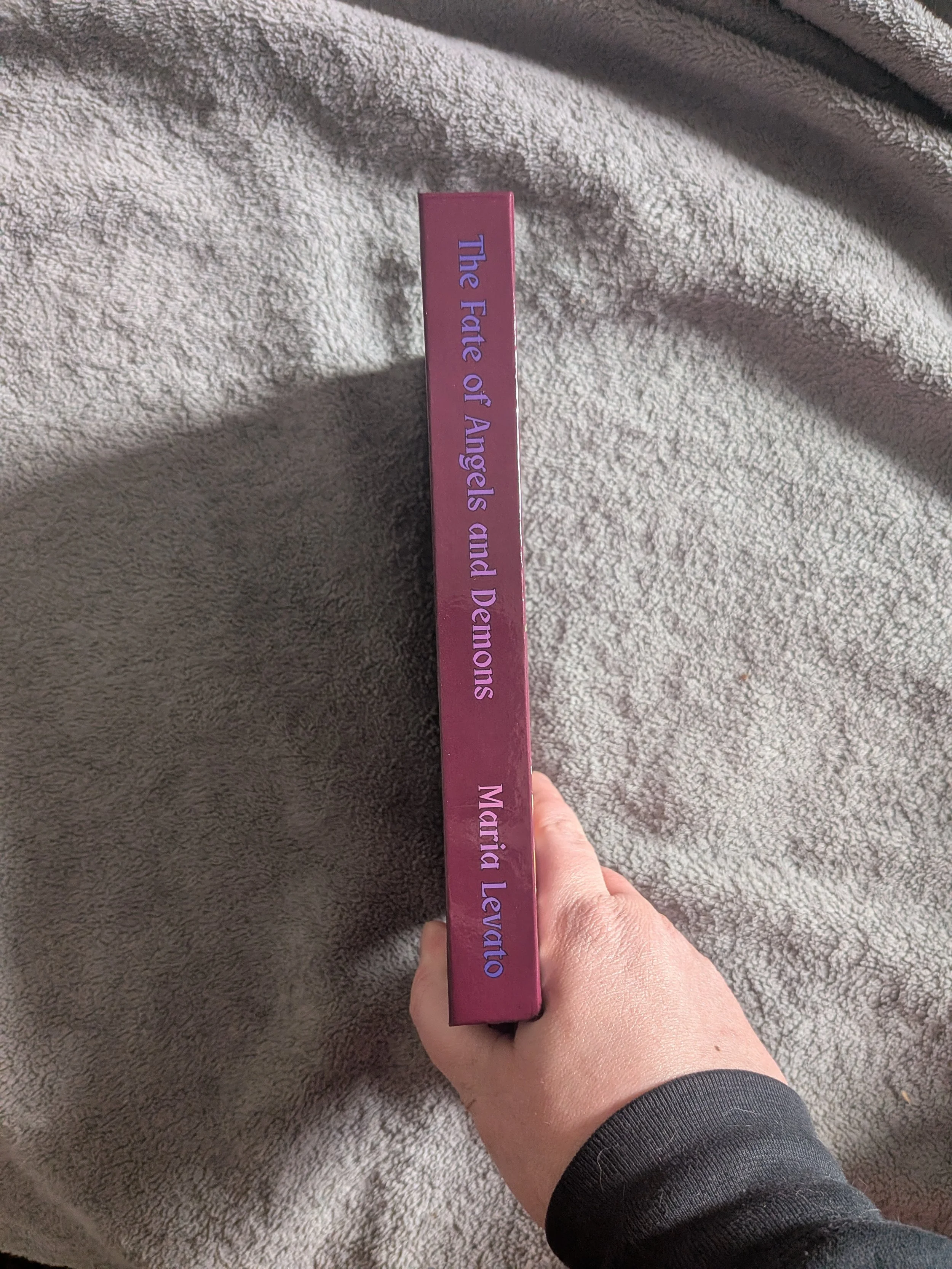 Spine view of a book titled "The Fate of Angels and Demons" by Maria Levato. Special Edition Hardcover