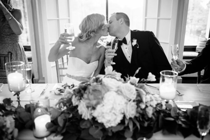 40.-Blackstone-Chicago-Wedding.-Pen-Carlson.-Sweetchic-Events.-bride-and-groom.-toast.-kiss.-garland.-head-table.-black-and-white.-680x454.jpg