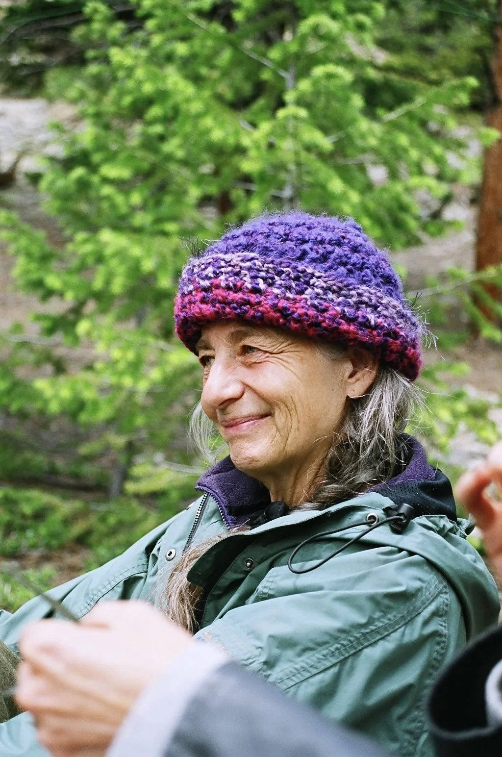 Sage Hamilton in a jacket and winter beanie, appearing reflective and enjoying the beauty of nature on the property at Sage Programs in Boulder, Colorado.