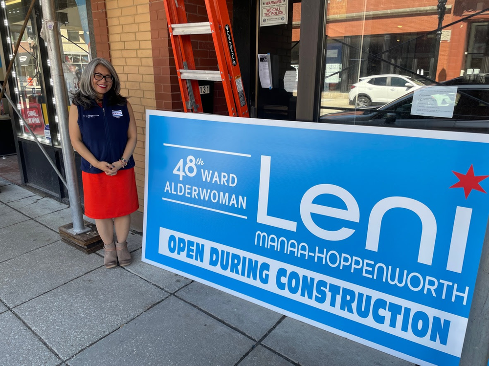 Ald. Manaa-Hoppenworth poses with a sign stating that the 48th Ward Office remains open during construction.