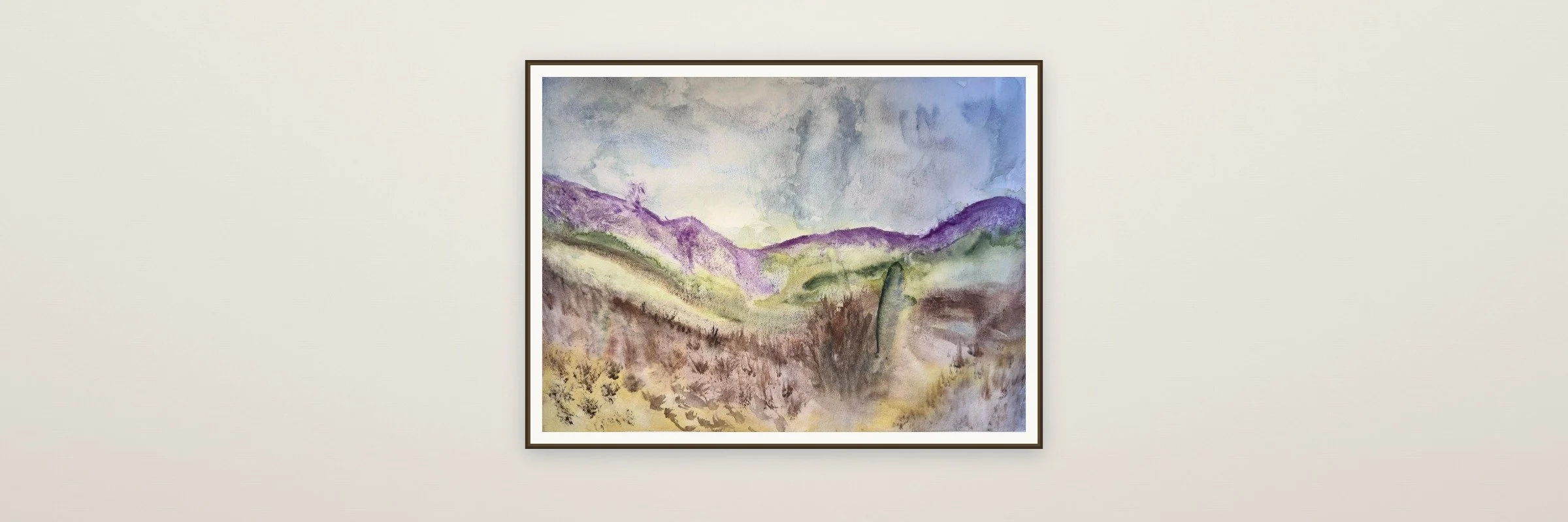 Watercolor painting of rolling hills and mountains with purple, green, and yellow tones under a cloudy sky by RAchael St.Claire.