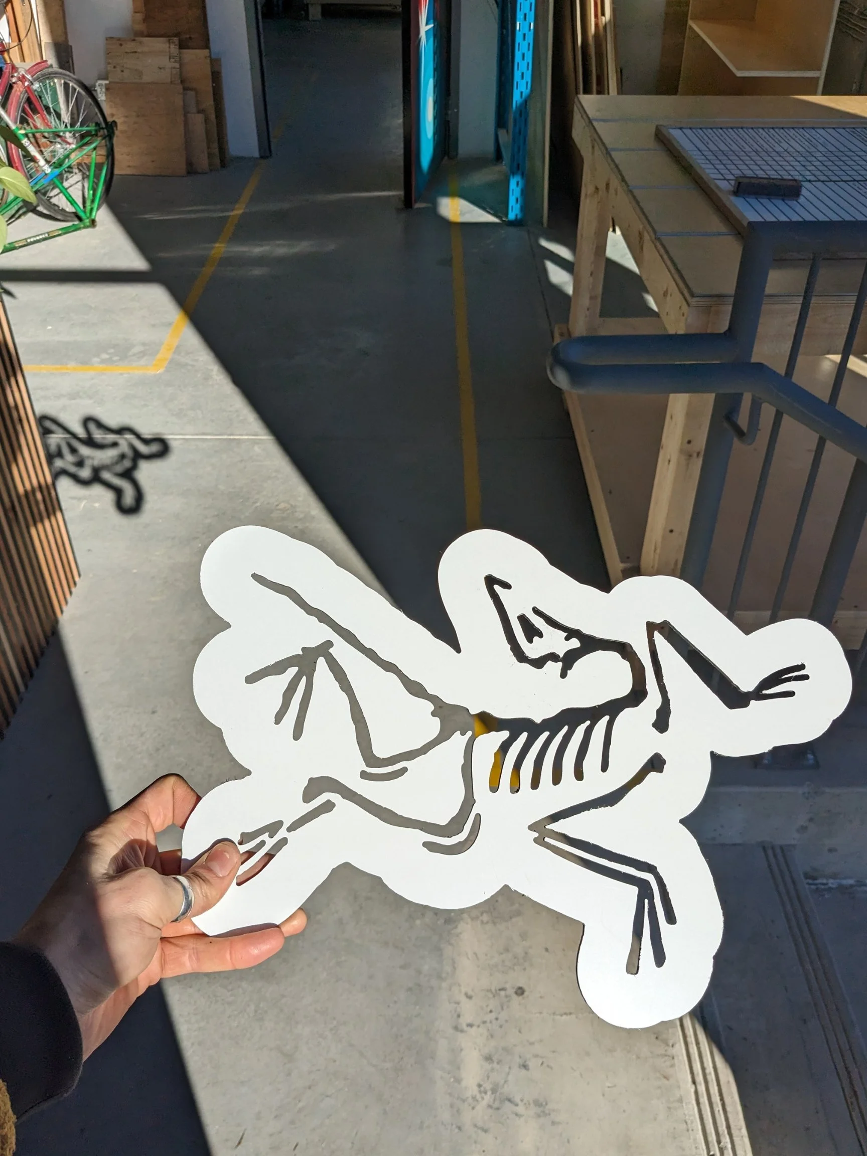 Person holding a white cutout of an animal skeleton in a workshop setting.