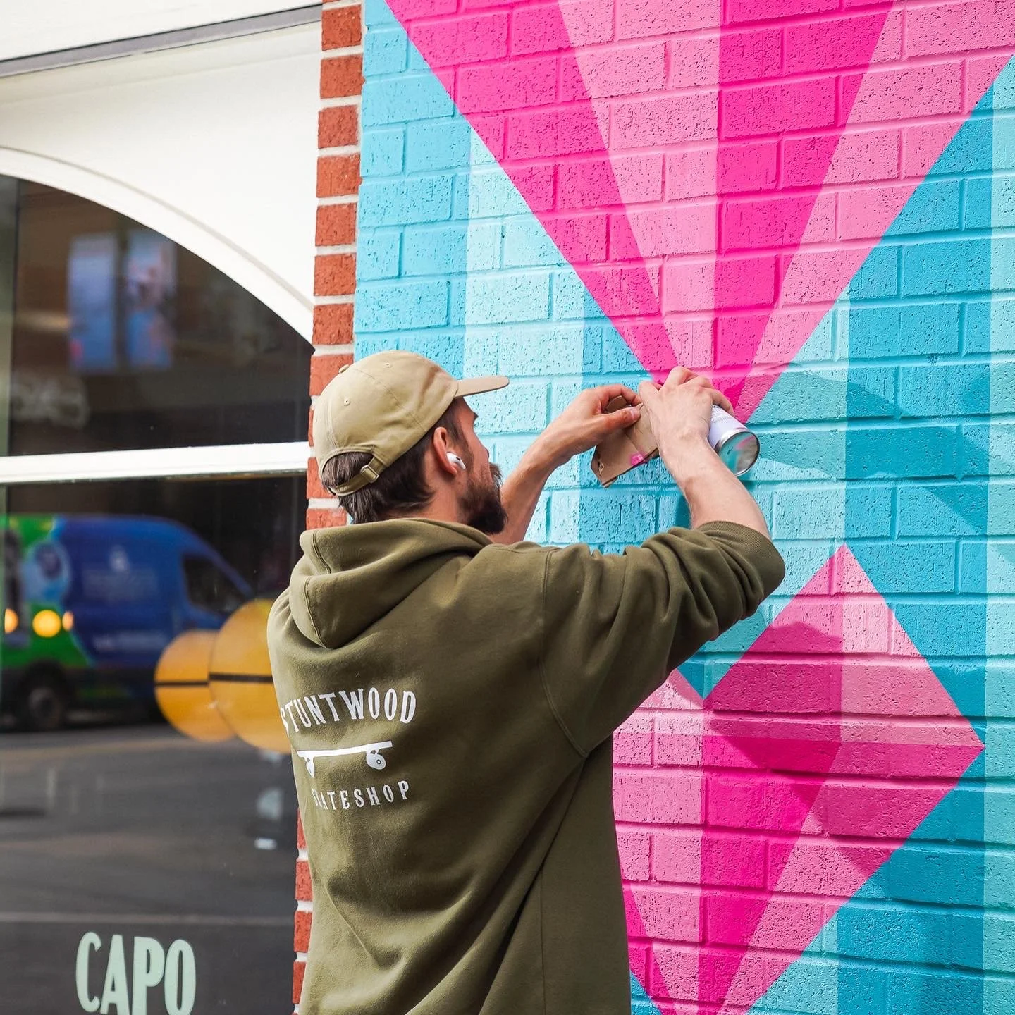 Artist painting colorful geometric mural on brick wall