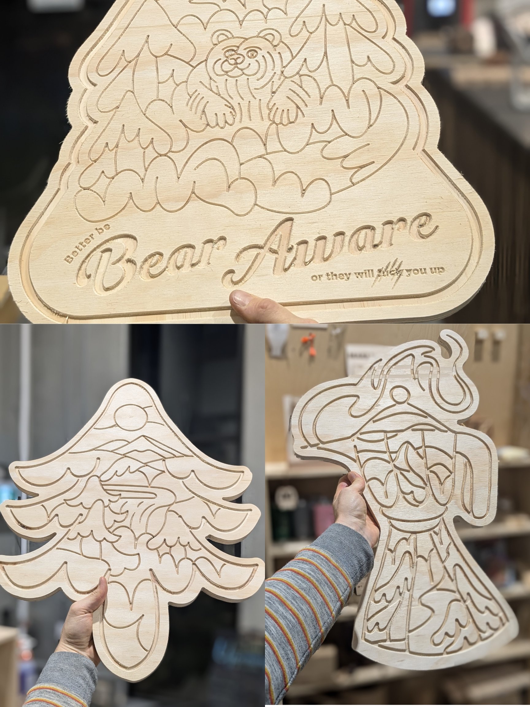 Three wooden cutouts being held, featuring intricate engraved designs: one with a bear and text 'Bear Aware,' another with a tree and landscape scene, and a third with a stylized lantern and flowing patterns.