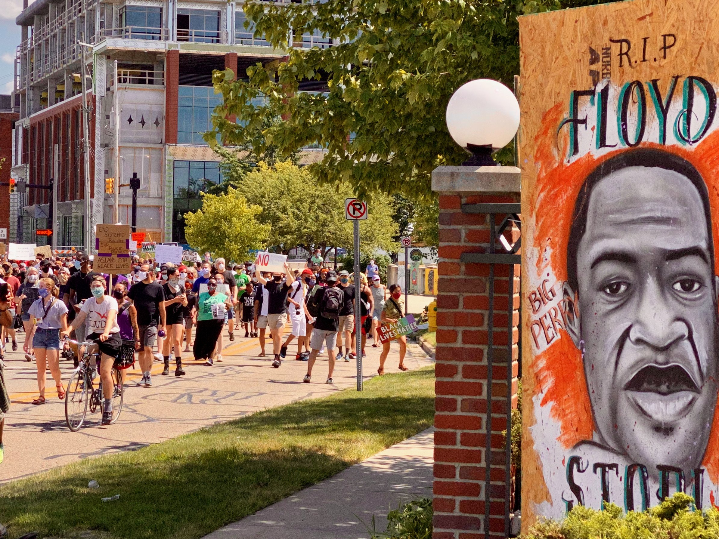 Hundreds of people continue the call for racial justice in Kalamazoo on July 11, walking past boards that were used by businesses downtown and were turned into artwork.