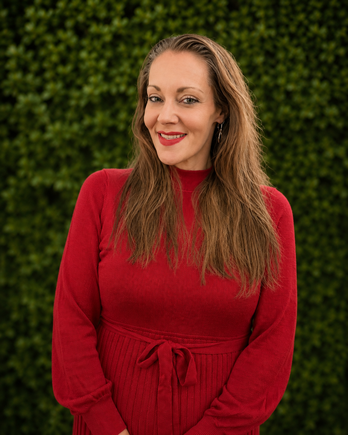 Woman in red shirt with red lipstick stands in front of Gabrella Manor smiling