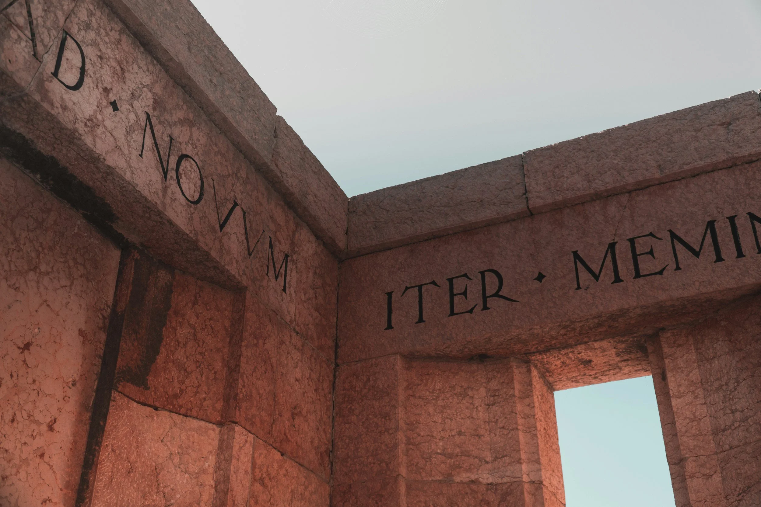Stone monument with Latin inscriptions on a clear sky background.