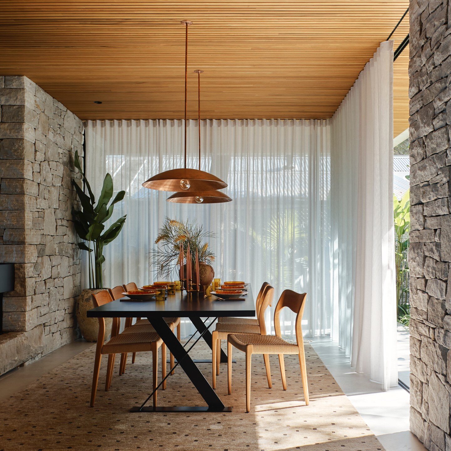 We love the warmth of this dining space, highlighted by the incredible stonework, timber cladded ceilings &amp; light coming through the sheer curtains. Definitely a welcoming space for a meal.