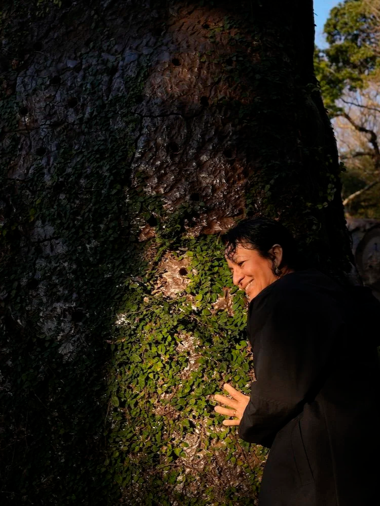 Portrait of Ximena (Elgueda Ward Studio co-founder) beside a large tree at The Mountain Plaza in Mihama, Aichi.／愛知県美浜町の山の広場®で、大きな木のそばに立つElgueda Ward Studio共同代表のポートレート。