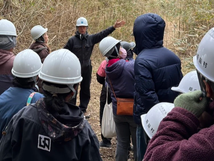 CCI participants wearing safety helmets listen during a field visit to the Shiroyama quarry in Himeshima, Oita. / 大分県姫島村の城山採石場で、現地視察中に説明を聞くヘルメット姿のCCI参加者たち。