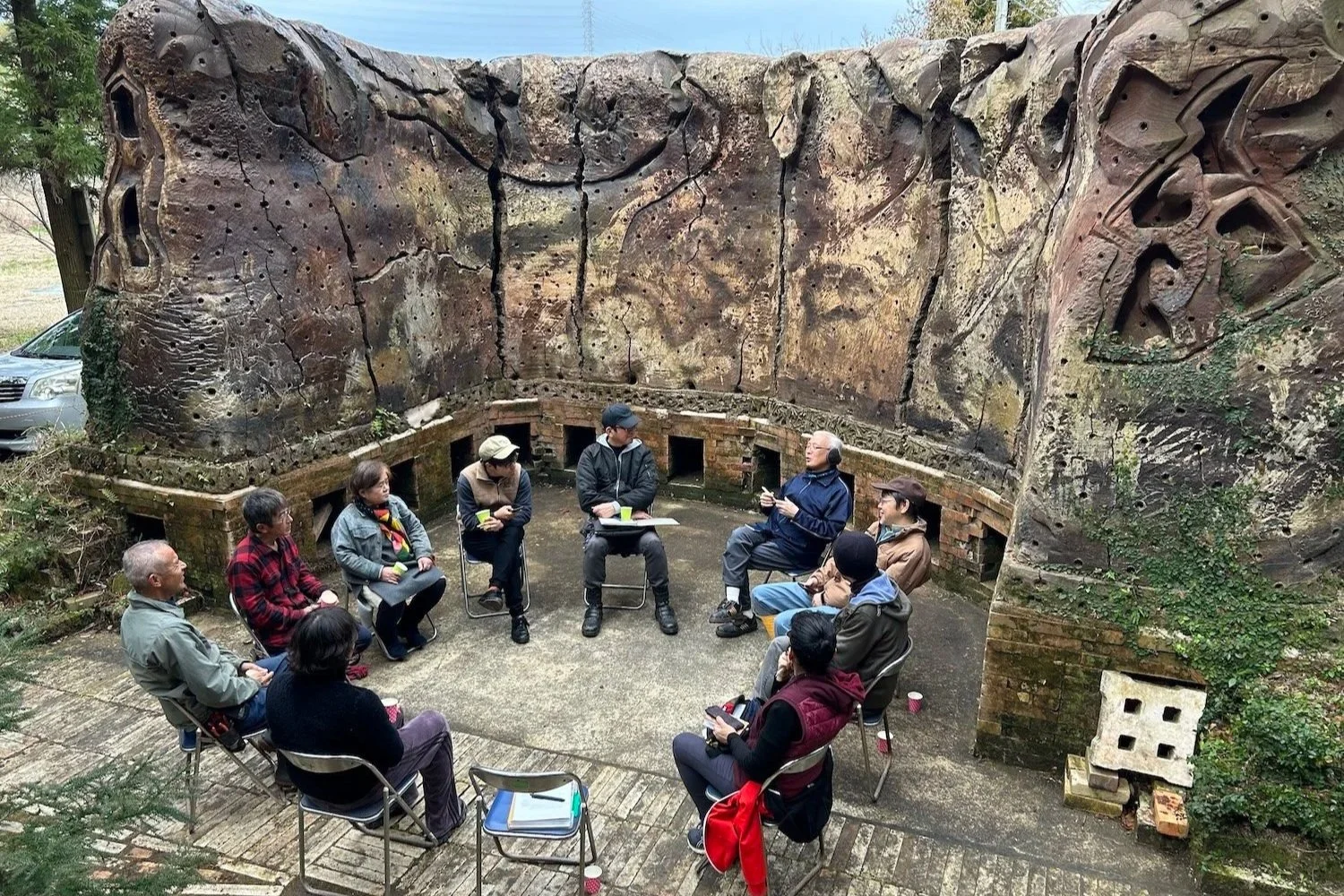People seated in a circle inside The Mountain Plaza ceramic amphitheater during a CCI community gathering in Mihama, Aichi.  愛知県美浜町の山の広場®・焼物野外劇場で、CCIの地域交流の集まりに参加し、輪になって座る人々。