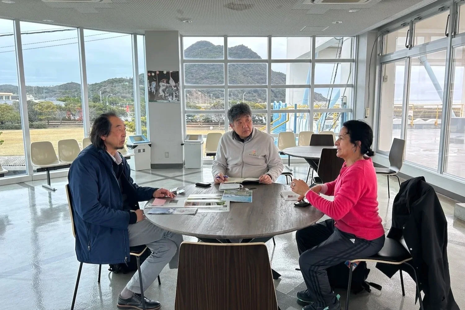 Representatives from three nonprofit organizations in conversation around a table at Himeshima Port, Oita. 大分県姫島村の姫島港で、テーブルを囲んで話し合う3つのNPO法人の関係者。