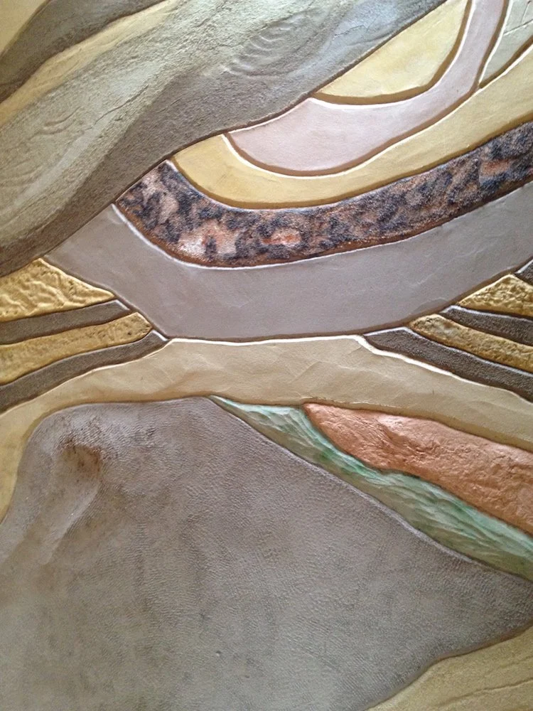 Close view of the completed GODAI earthen wall showing curved bands of differently colored soils, textures, and handmade surface finishes. 完成した《GODAI / 五大》の土壁のクローズアップ。異なる色と質感をもつ土の曲線状の層と、手仕事による表面の仕上げが見える。
