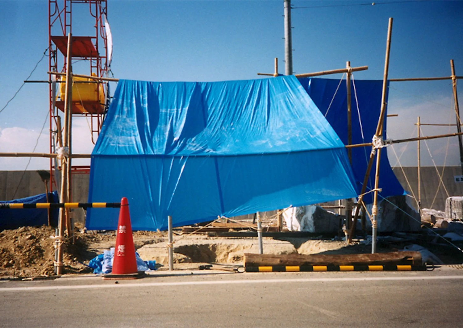 Plaza de Sora construction site with scaffolding and protective blue sheeting at Onizaki Yacht Harbor, Tokoname, 2000. / 2000年、常滑市鬼崎ヨットハーバーで足場と青いシートに覆われた《空の広場》の制作現場。