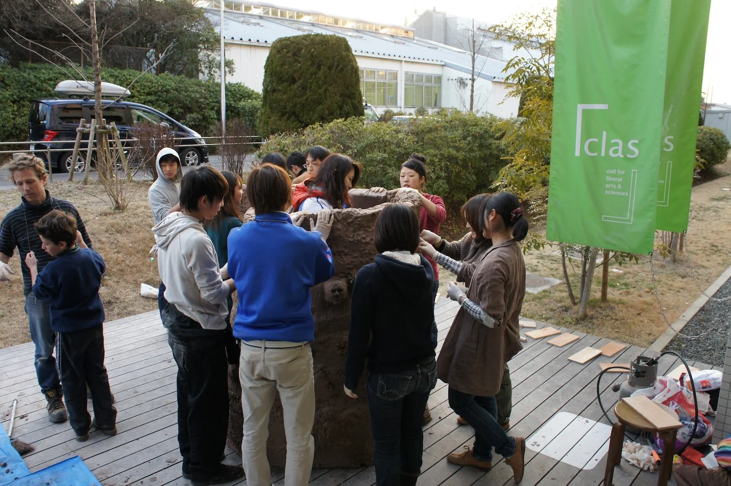 Nagoya University students shape and press raw clay by hand during the Common Ground collaborative workshop outside Clas Gallery. 《Common Ground》の共同制作ワークショップで、名古屋大学の学生たちがClas Gallery屋外で生の粘土を手で押し、形づくっている様子。