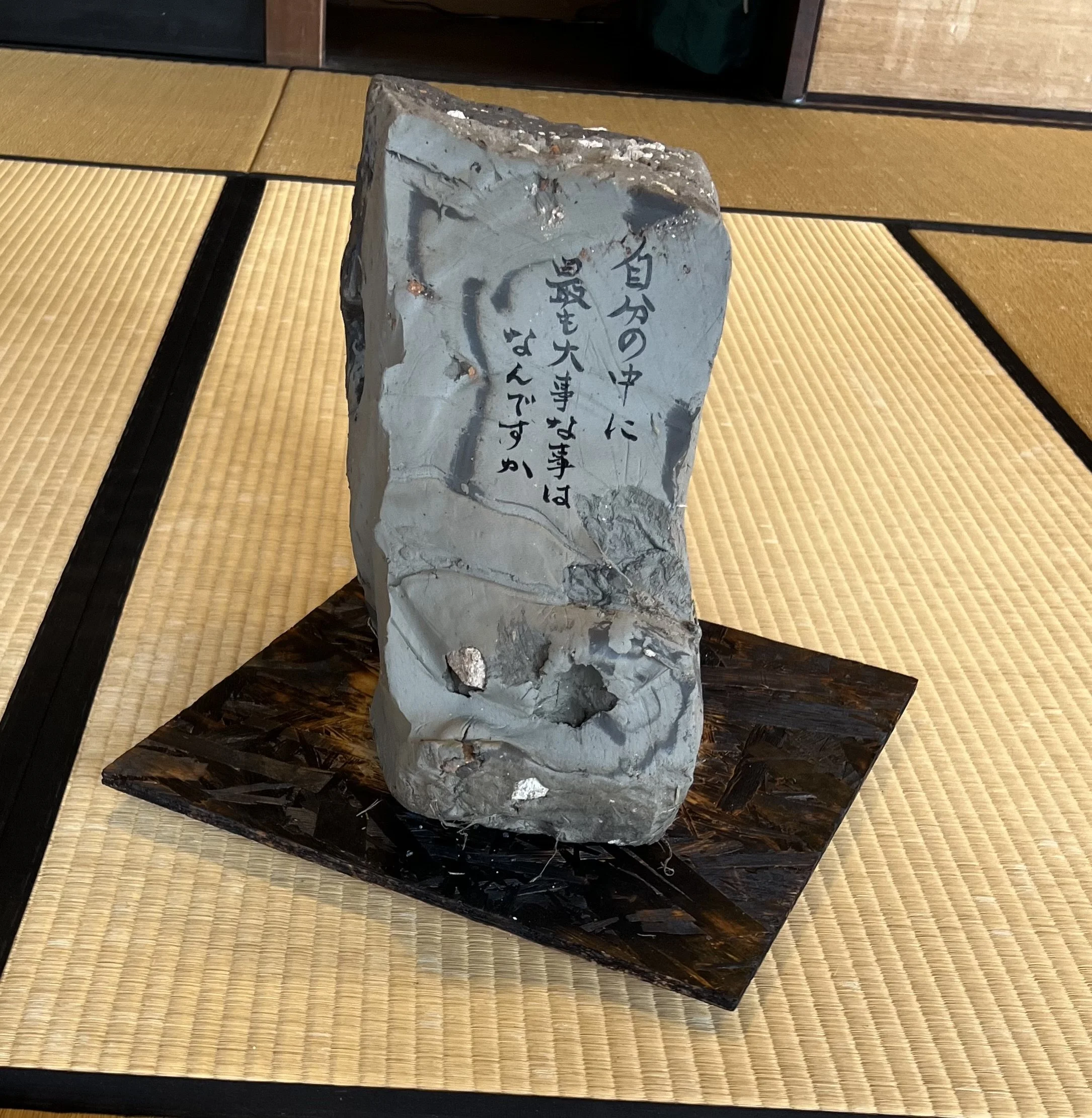 Upright raw-clay sculptural form with handwritten Japanese calligraphy in the Sealed by Time installation at the Former Nakano Hanroku Residence. / 旧中埜半六邸の《Sealed by Time》で、日本語の書が表面に記された生の粘土による立ち上がった造形。
