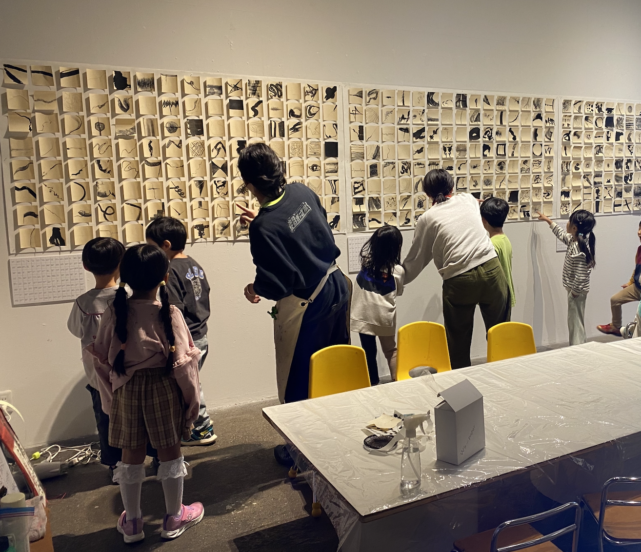 Children and instructors take part in a collaborative KIC English-language learning activity surrounded by an installation of paper artworks in Aichi, Japan.  愛知県のKIC英語教育プログラムで、紙作品のインスタレーションに囲まれながら、協働型の学習活動に参加する子どもたちと講師。