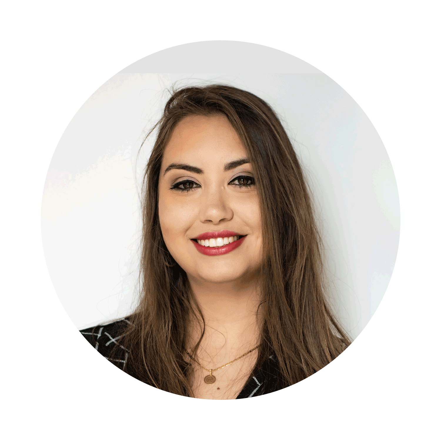 A woman with brown hair, smiling, wearing red lipstick, black top, and a gold necklace, against a white background.