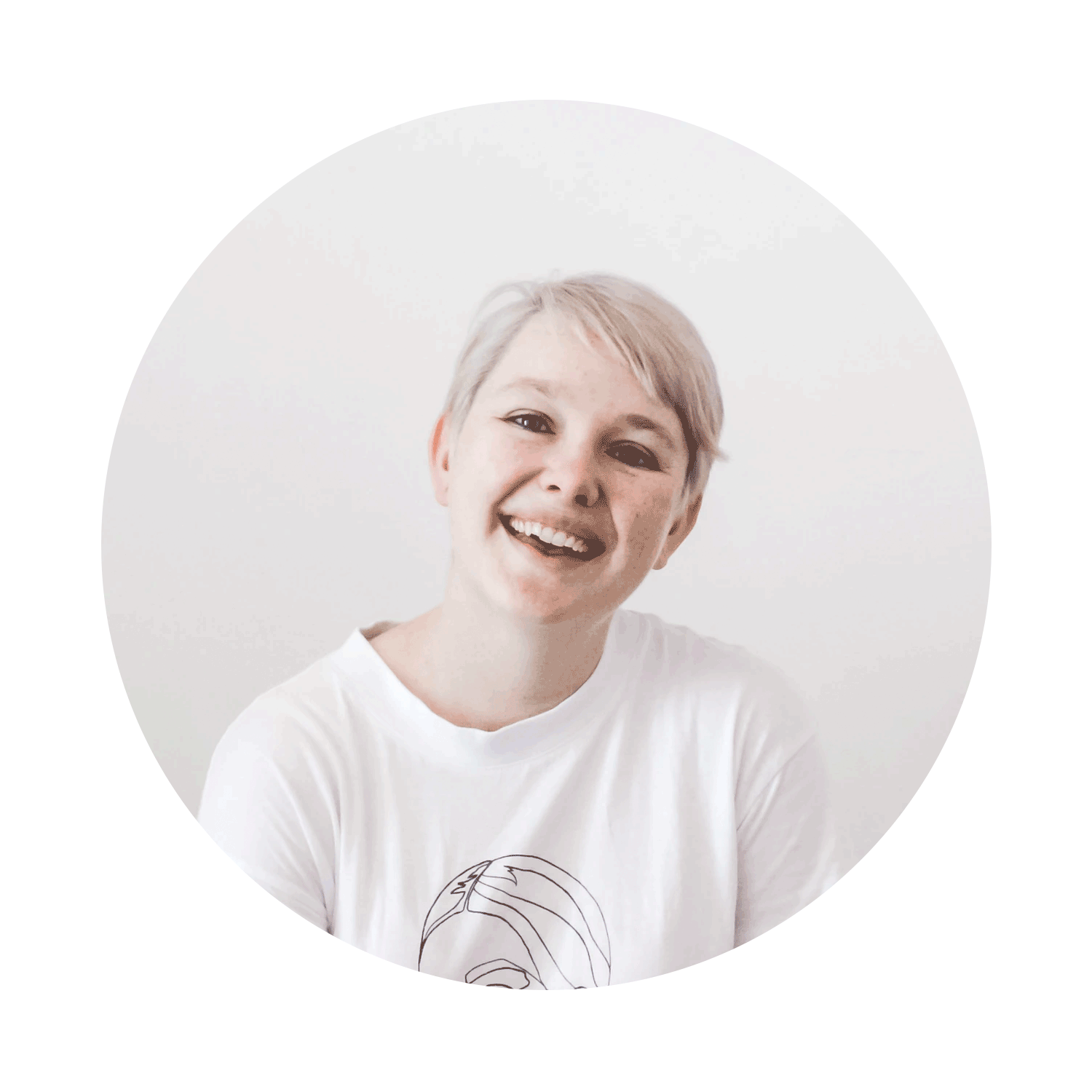 Smiling woman with short, light-colored hair, wearing a white T-shirt with a line drawing, against a plain white background.