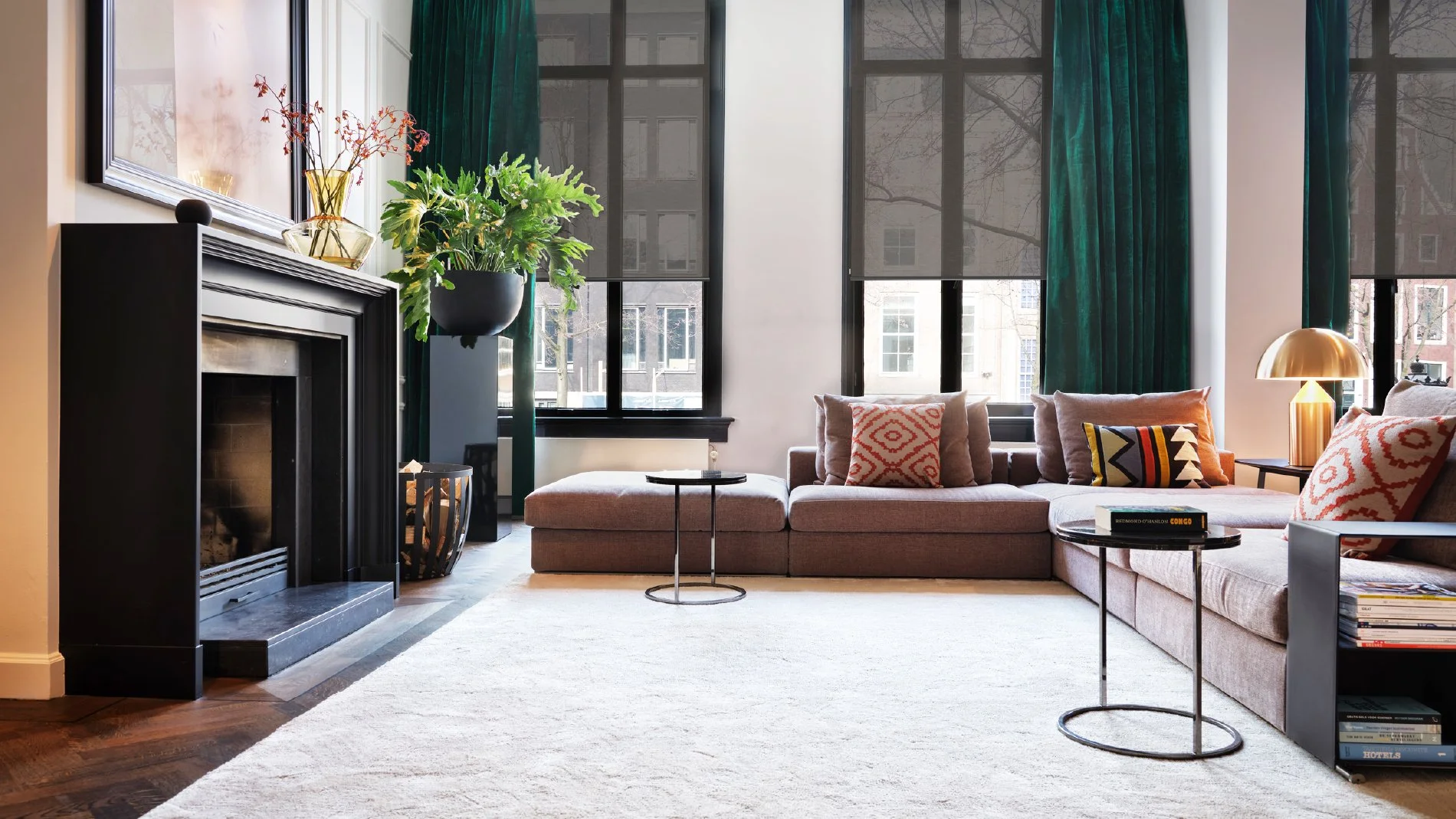 Moderne bad med stort svart badekar, servant i hvitt på en trebenk, og store vinduer med hvite persienner.