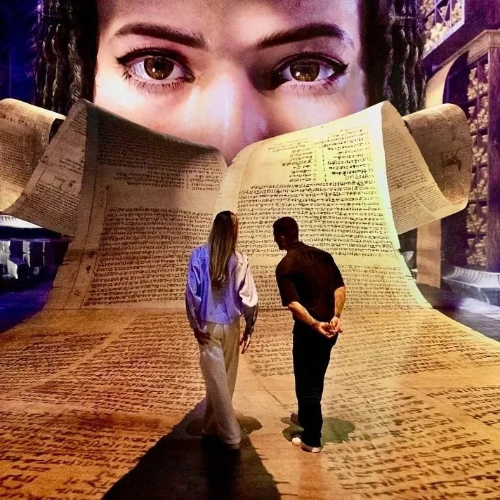 Visitors exploring the immersive Cleopatra exhibition in London featuring giant ancient scrolls and interactive historical displays.