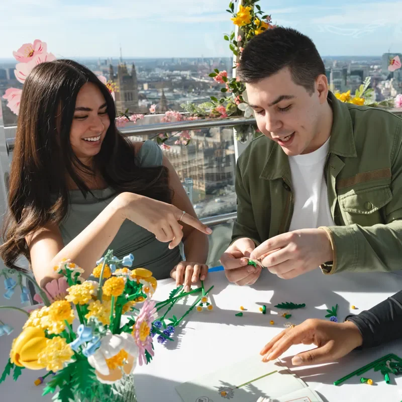 People creating LEGO botanical flowers at London experience, hands-on building activity with city skyline views and colourful floral sets