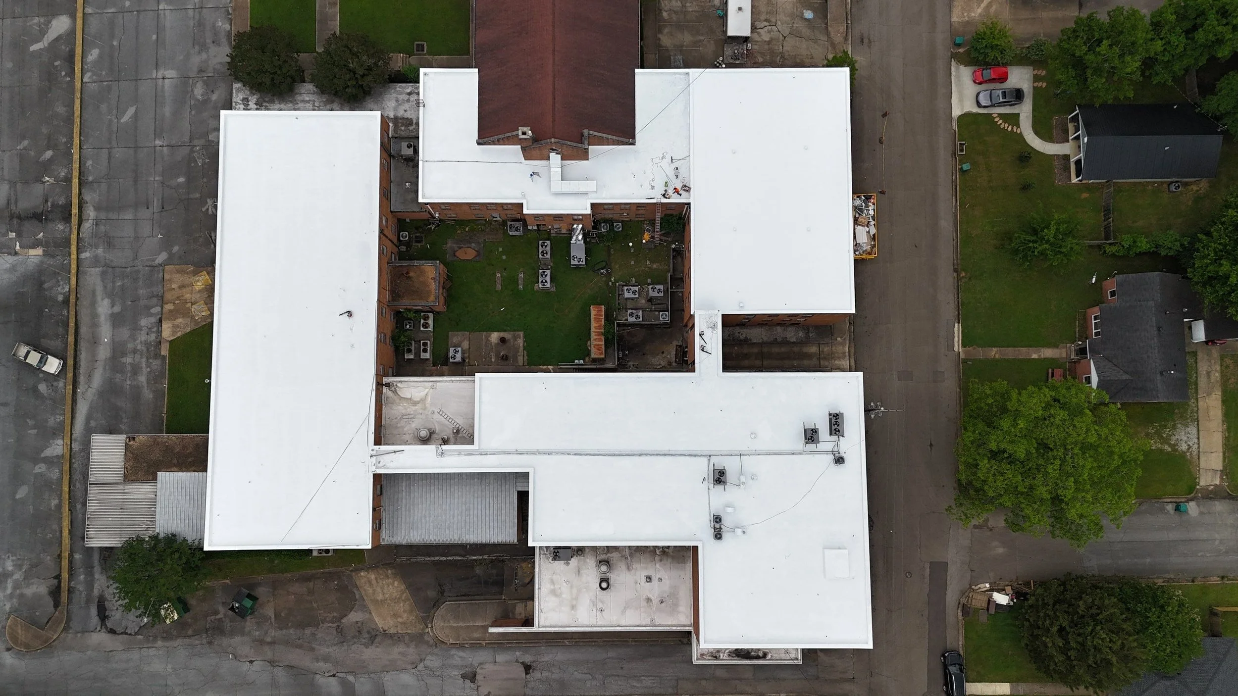 A large commercial building with 4 white, newly coated flat roofs