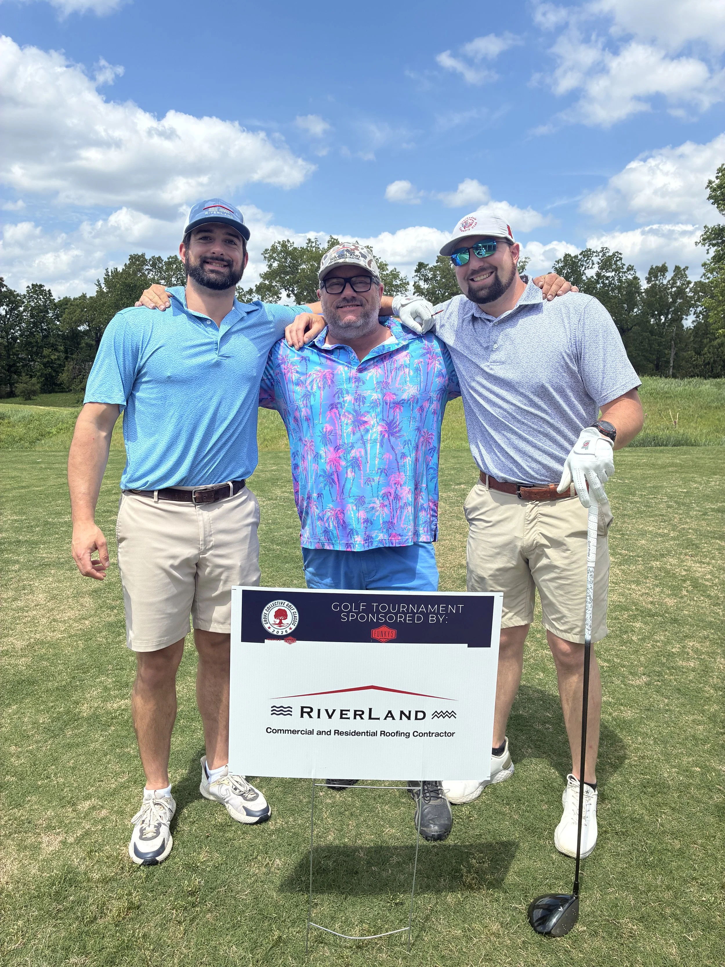 3 people in front of the sponsored hole sign at the Grove Collective golf tournament