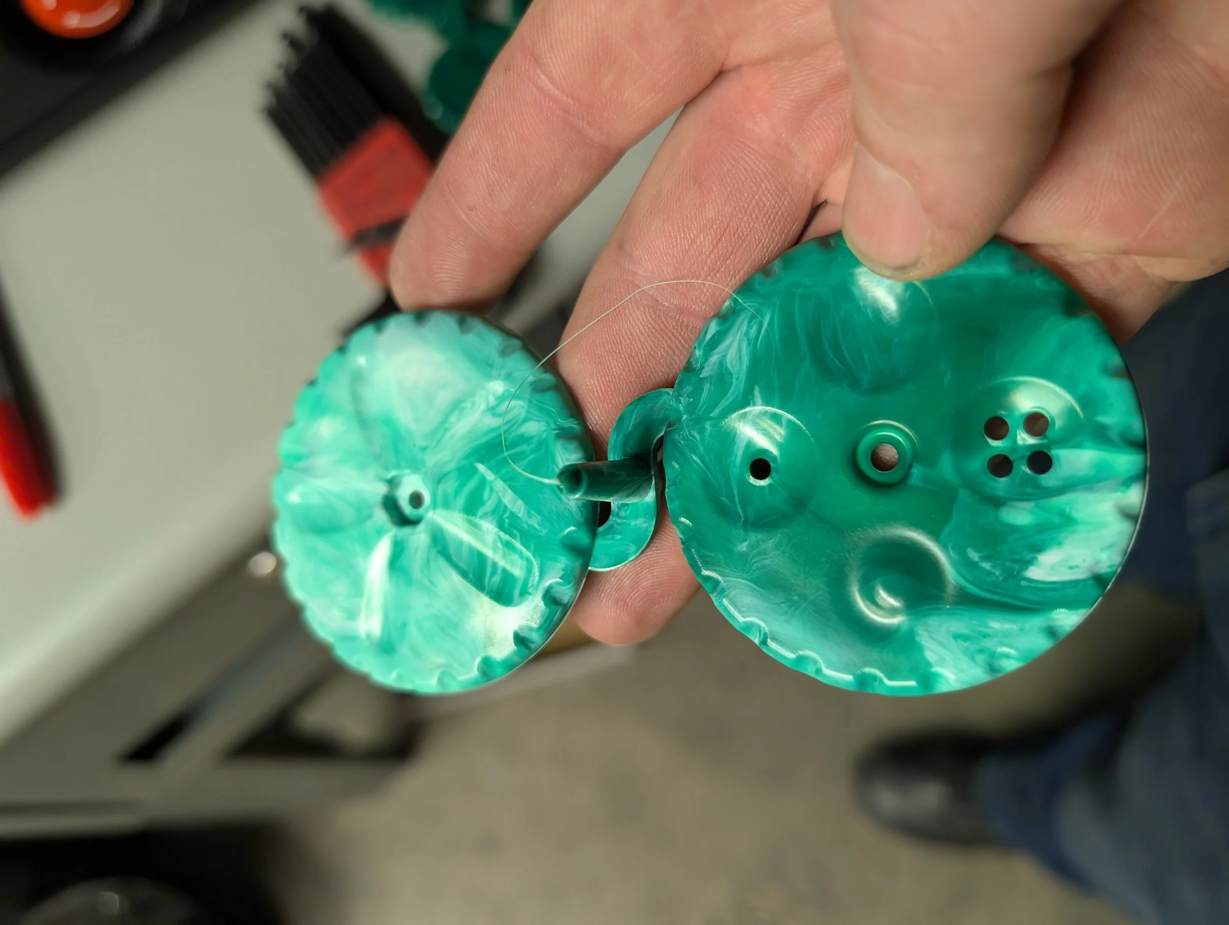 This picture shows the parts for a Palm Twirl fidget spinner toy/tool fresh out of the injection molding machine. Sprue, gates, and runners still attached.